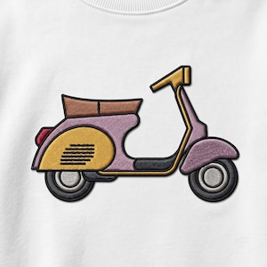 Op de afbeelding: Een wit sweatshirt met een borduursel van een scooter in vintage-stijl. De scooter is voornamelijk lavendelkleurig met een geel zijpaneel, een bruine zitting en zwarte wielen. Het ontwerp bevat zwarte omlijningen en een klein rood achterlicht.