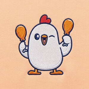 May include: An embroidered patch on a light peach fabric featuring a white cartoon chicken with a red comb, dark blue outlines, and orange feet. The chicken is winking and holding a golden-brown fried chicken leg in each raised wing.