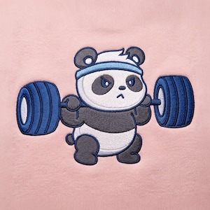 May include: A light pink fabric featuring an embroidered graphic of a panda wearing a light blue headband. The panda has a determined expression and is lifting a barbell with large, dark blue weight plates on each side of the bar.