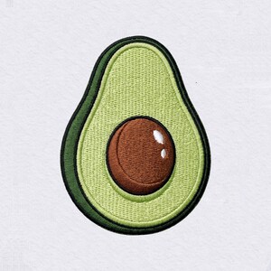 Pode incluir: Um emblema bordado em forma de metade de um abacate. O design apresenta um centro verde-claro, uma borda externa verde-escura e um caroço castanho no meio com dois pequenos reflexos brancos na superfície para indicar uma textura brilhante.