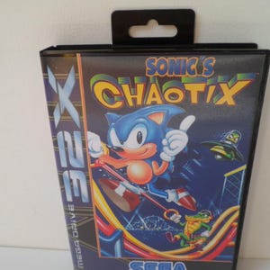 Könnte beinhalten: Eine schwarze Kunststoff-Videospielhülle für die Sega 32X-Konsole mit dem Titel Sonic's Chaotix. Das Cover zeigt die blaue Figur Sonic, ein grünes Krokodil und ein kleines Flugobjekt vor einem dunkelblauen Hintergrund.