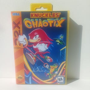 Op de afbeelding: Een gele plastic videospelhoes voor het Sega 32X-systeem met de titel Knuckles' Chaotix. De hoes toont het rode personage Knuckles die een gouden ring vasthoudt, een groen krokodilpersonage en een klein vliegend groen wezen op de afbeelding.