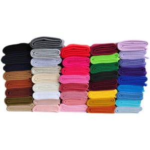 May include: A collection of folded ribbed knit fabric swatches arranged in five vertical stacks. The fabric pieces display a wide spectrum of colors including black, gray, red, pink, green, yellow, blue, purple, brown, and white tones.