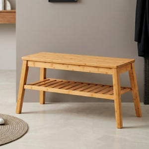 May include: A rectangular bamboo bench featuring a smooth solid top surface and a lower slatted shelf for storage. The bench is supported by four sturdy, slightly angled legs, showcasing the natural light brown wood grain throughout the structure.