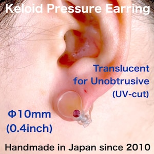May include: A translucent keloid pressure earring, 0.4 inches in diameter, with a small red gem. The text reads "Translucent for Unobtrusive (UV-cut)" and "Handmade in Japan since 2010."