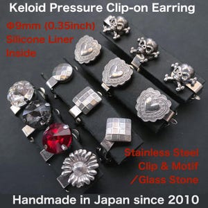 Puede incluir: Surtido de pendientes de clip con varios diseños, incluyendo calaveras, corazones y formas geométricas. Los pendientes son de acero inoxidable y presentan piedras de vidrio. El texto en la imagen dice "Handmade in Japan since 2010". Cada pendiente mide aproximadamente 9 mm.