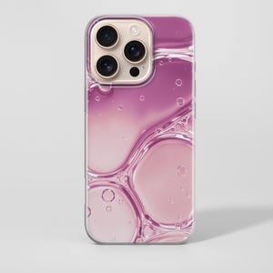 May include: A smartphone case featuring a glossy, abstract design of translucent pink liquid bubbles and circular droplets. The case has a clear border and a cutout for the triple-lens camera system located on the upper left corner of the device.