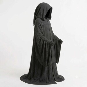 May include: A full-length, dark charcoal gray hooded cloak featuring long, wide sleeves and a textured fabric finish. The garment drapes to the floor, creating a voluminous silhouette with a deep hood that obscures the upper portion of the form.