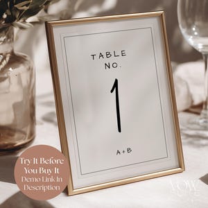 May include: A vertical rectangular table number sign in a thin gold metal frame. The white card features the black text TABLE NO. at the top, a large number 1 in the center, and A+B at the bottom, all enclosed within a thin black border line.