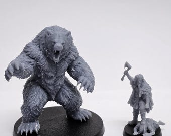 May include: A grey unpainted resin miniature of a large roaring bear standing on a round black base, positioned next to a smaller grey resin miniature of a warrior holding an axe and standing over a fallen figure on a round black base.