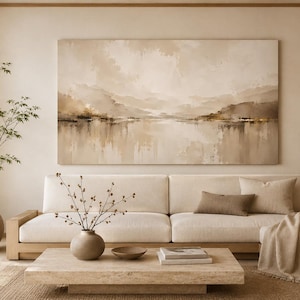 Könnte beinhalten: Ein großes horizontales Landschaftsgemälde in neutralen Beige- und Brauntönen hängt über einem niedrigen cremefarbenen Sofa. Der Raum verfügt über einen Couchtisch aus hellem Holz, eine Keramikvase mit dünnen Zweigen und eine Topfpflanze.