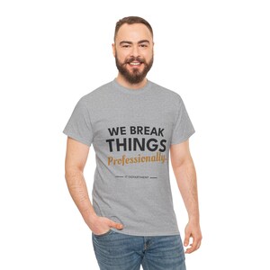 May include: A heather gray short-sleeve t-shirt featuring the black text WE BREAK THINGS and the gold text Professionally. Below this, the text IT DEPARTMENT is printed between two horizontal lines. The shirt has a crew neckline.