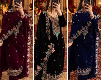 May include: Three velvet salwar kameez sets in burgundy, black, and navy blue. Each set features long-sleeved tunics, matching trousers, and a draped dupatta, all adorned with intricate silver embroidery, colorful accents, and small star motifs.
