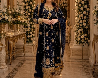 May include: A dark navy blue long-sleeved tunic and matching wide-leg trousers set featuring intricate gold embroidery, sequin embellishments, and a coordinating sheer dupatta. The garment displays a round neckline with gold detailing and a hemline.