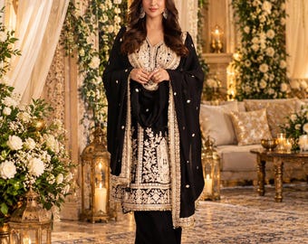 May include: A black three-piece outfit consisting of a long-sleeved tunic, matching trousers, and a shawl, all featuring intricate gold embroidery along the hemlines, neckline, and front panels, with a solid black fabric base throughout.