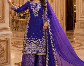 May include: A royal blue long-sleeved tunic featuring intricate silver embroidery around the neckline and hem, paired with wide-leg trousers in a matching blue with a subtle metallic pattern and a sheer blue dupatta with a decorative silver border.