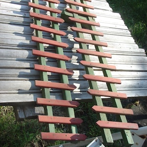 May include: Two wooden fence panels with green and red painted slats. The panels are leaning against a wooden surface.