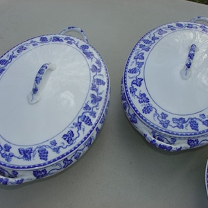 May include: Two white oval serving dishes with blue and white grapevine designs and lids. The lids have a handle on top.