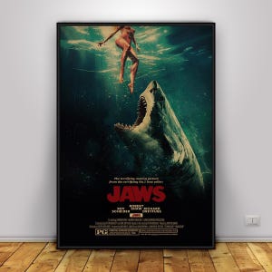 Könnte beinhalten: Ein Filmplakat für Jaws, das einen großen Hai zeigt, der nach oben in Richtung einer an der Oberfläche schwimmenden Person schwimmt. Der Titel Jaws ist in fetten roten Buchstaben gedruckt, darunter die Namen Roy Scheider, Robert Shaw und Richard Dreyfuss.
