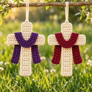 May include: Two crocheted crosses hanging from a branch. Each cross is made of cream-colored yarn with a draped fabric-like piece attached to the front. One cross features a deep purple drape, while the other has a dark red drape.