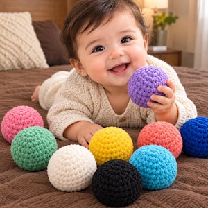 May include: A collection of nine small, round, crocheted yarn balls in various solid colours including purple, pink, green, yellow, white, black, coral, light blue, and dark blue, each featuring a textured, knotted surface pattern.