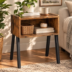 May include: A rectangular side table with a dark brown wood grain finish and four black metal legs. The table features an open storage compartment containing a woven basket and two stacked books with the text Live Beautifully At Home.