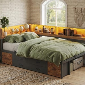 May include: A corner bed frame with a built-in headboard shelf featuring integrated warm lighting. The frame includes dark grey storage drawers and wood-grain panels. The bed is dressed in a sage green comforter and pillows, with globes, vases, and books displayed on the illuminated shelf.