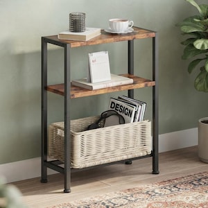 May include: A three-tier shelving unit featuring a black metal frame and two brown wood-grain shelves. The top shelf holds a candle, a book, and a teacup. The middle shelf holds a calendar and a book. The bottom shelf contains a woven basket.