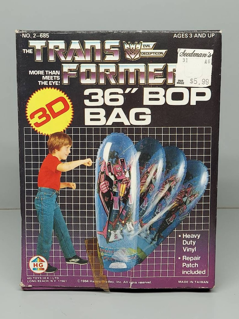 May include: A box for a 36-inch Transformers Bop Bag. The box features a 3D image of a Transformer character on a blue and purple inflatable bag. The box is black with yellow and red accents. The text on the box reads "Transformers 36" Bop Bag".