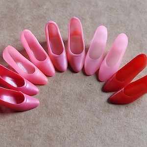 Puede incluir: Una colección de nueve zapatos de tacón alto de color rosa y rojo dispuestos en semicírculo.