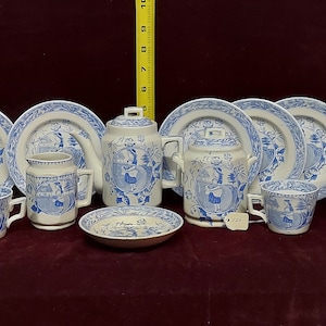 May include: A vintage blue and white porcelain tea set with a floral design. The set includes a teapot, creamer, sugar bowl, four cups, and four saucers.