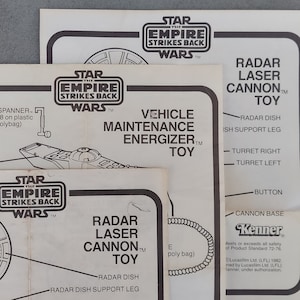 May include: A Star Wars: The Empire Strikes Back toy instruction sheet for the Vehicle Maintenance Energizer toy. The sheet is black and white and features a line drawing of the toy. The sheet also includes instructions for assembling the toy.
