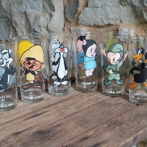 Puede incluir: Seis vasos vintage de Looney Tunes con personajes como Pepe Le Pew, Speedy Gonzales, Silvestre, Petunia Pig, Elmer Fudd y el Pato Lucas. Cada vaso presenta una ilustración diferente y el nombre del personaje.