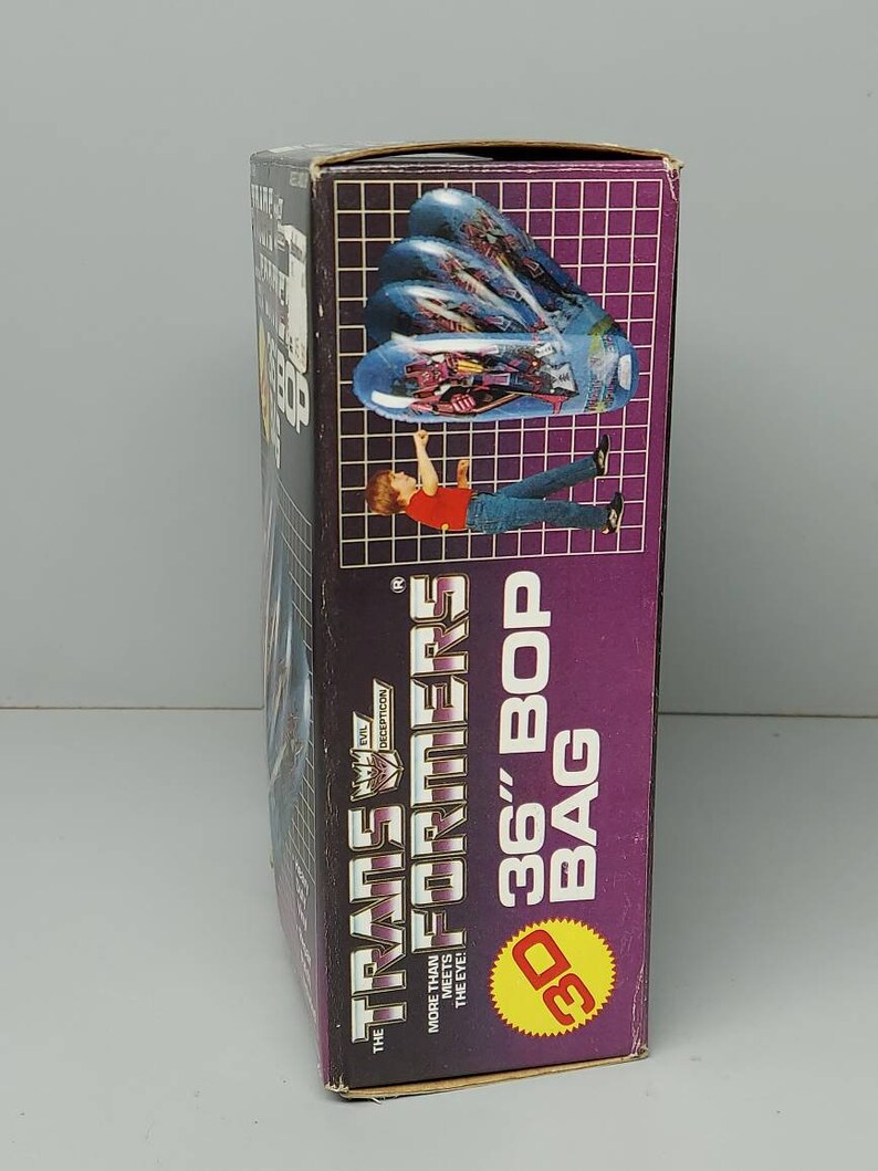 May include: A cardboard box with a purple background and the text "The Transformers 36" Bop Bag" in white. The box features a 3D image of a blue and silver robot.