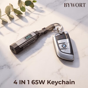 Puede incluir: Un llavero 4 en 1 de 65W plateado y negro con una pantalla digital que muestra 240, unido a una llave de coche BMW mediante una anilla metálica y una correa de tela gris. El texto BYWORT y 4 IN 1 65W Keychain son visibles en la imagen.