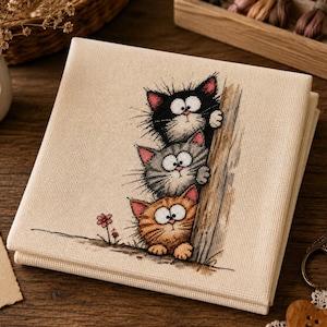May include: A square piece of beige fabric featuring a cross-stitch embroidery of three stacked cats peeking from behind a wooden post. The top cat is black, the middle is gray striped, and the bottom is orange striped, all with wide eyes.