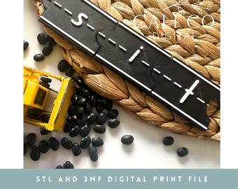 May include: A black 3D printed toy road track segment with white dashed lines, featuring interlocking puzzle-style edges. A yellow toy construction vehicle and scattered black beans are positioned nearby. The text reads STL AND 3MF DIGITAL PRINT FILE.