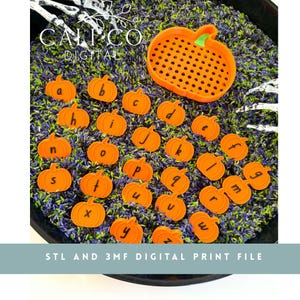 Puede incluir: Una colección de fichas naranjas con forma de calabaza, cada una grabada con una letra minúscula del alfabeto, dispuestas sobre una base de arroz morado y verde. Incluye un tamiz naranja con forma de calabaza y decoraciones de manos esqueléticas.