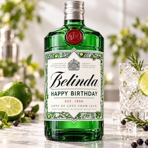 May include: A green glass bottle of gin with a silver screw cap and a red wax seal. The label features the text Belinda, HAPPY BIRTHDAY, EST. 1990, LOTS OF LOVE FROM JACK, and botanical illustrations framed in a white geometric border.