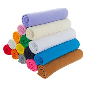 Op de afbeelding: Een verzameling zachte fleece stofrollen gestapeld in een piramidevorm. De kleuren omvatten lavendel, crème, wit, felblauw, bruin, roze, donkergrijs, geel, groen, oranje, rood en lichtgrijs, allemaal met een gladde textuur.