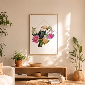 Pode incluir: Uma impressão de arte emoldurada apresentando um tucano empoleirado num galho, rodeado por flores tropicais vibrantes cor-de-rosa e amarelas e folhas verdes, tudo dentro de um contorno dourado fino em forma de diamante num fundo branco.