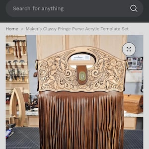 May include: A brown leather handbag featuring a top section with intricate floral tooling and a cutout handle. The bag has a central brass-colored turn-lock closure and a long, dense fringe that covers the entire lower body of the purse.