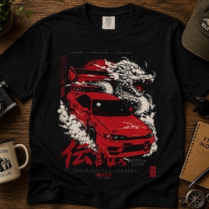 May include: A black short-sleeve t-shirt featuring a graphic print of a red sports car drifting with a white dragon illustration. The design includes Japanese characters, the text "LEGEND" and "TOKYO STREET LEGENDS", and a red sun background.