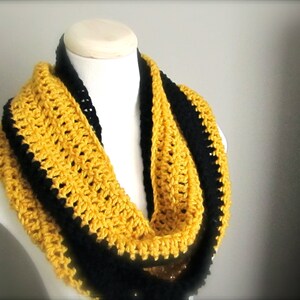 May include: A yellow and black crocheted infinity scarf. The scarf is made with a single crochet stitch and has a black border.
