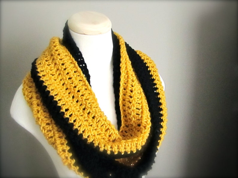 May include: A yellow and black crocheted infinity scarf. The scarf is made with a single crochet stitch and has a black border.