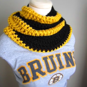 May include: A black and yellow crocheted neck warmer with a gray shirt with the word "BRUINS" printed on it.