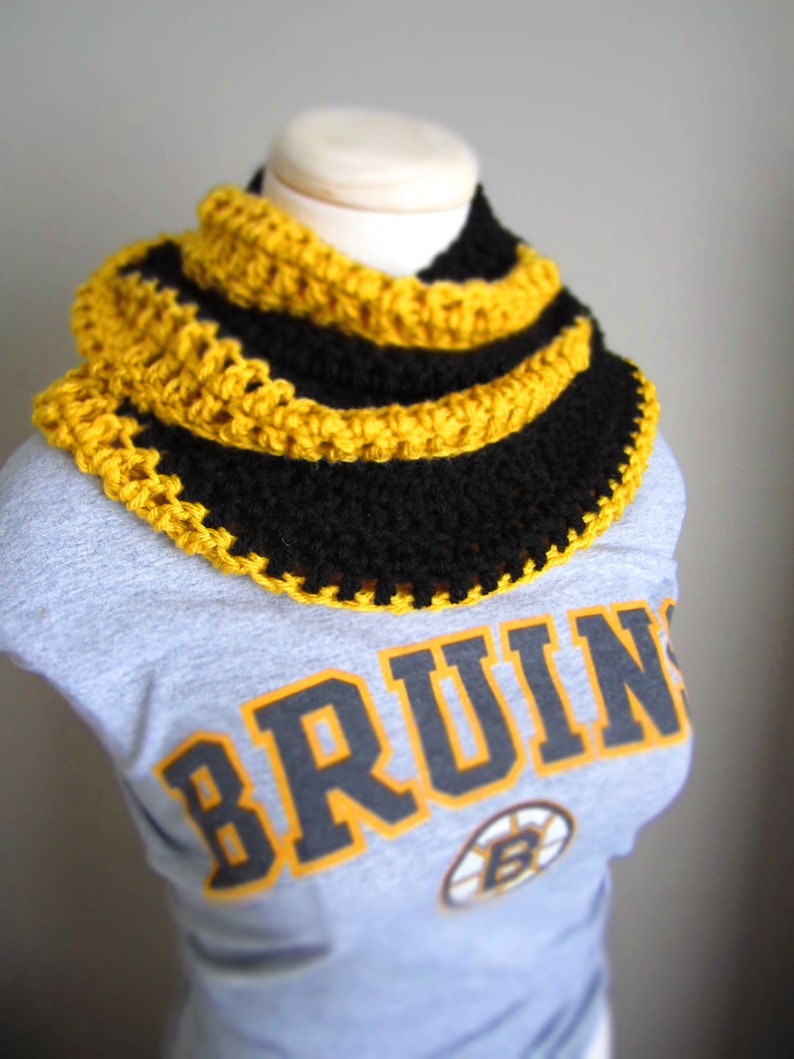 May include: A black and yellow crocheted neck warmer with a gray shirt with the word "BRUINS" printed on it.