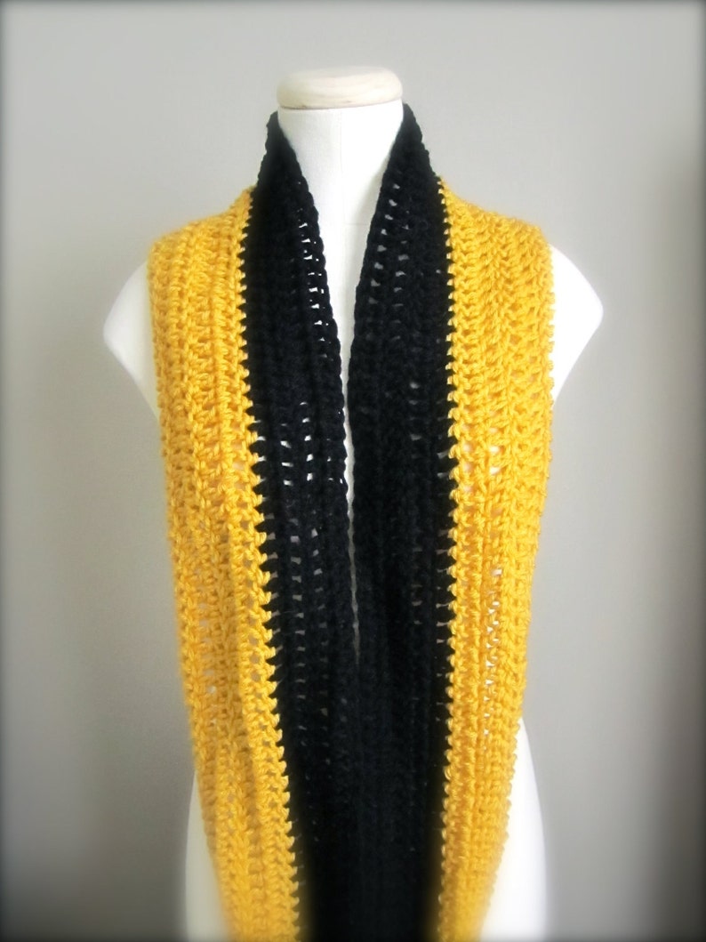 May include: A crocheted infinity scarf with black and yellow stripes. The scarf is made with a simple stitch pattern and is a great way to add a pop of color to any outfit.