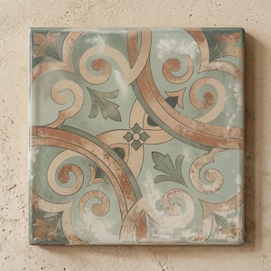 May include: A square ceramic tile featuring a symmetrical pattern of sage green and terracotta brown scrolls, leaves, and a central four-petaled flower. The surface has a weathered, distressed finish with muted tones and intricate curved lines.