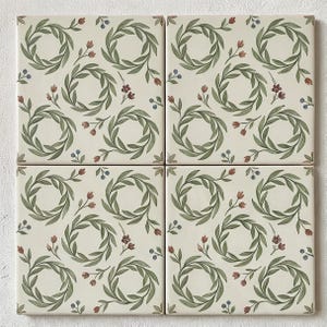 Puede incluir: Cuatro azulejos de cerámica cuadrados dispuestos en cuadrícula, con un patrón repetitivo de coronas de hojas verdes sobre un fondo crema. El diseño incluye pequeños capullos de flores rojas y diminutas bayas azules entre los motivos.